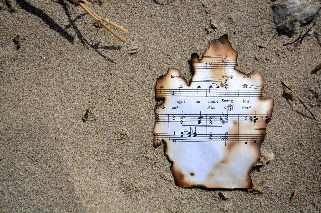 charred piece of sheet music on sand