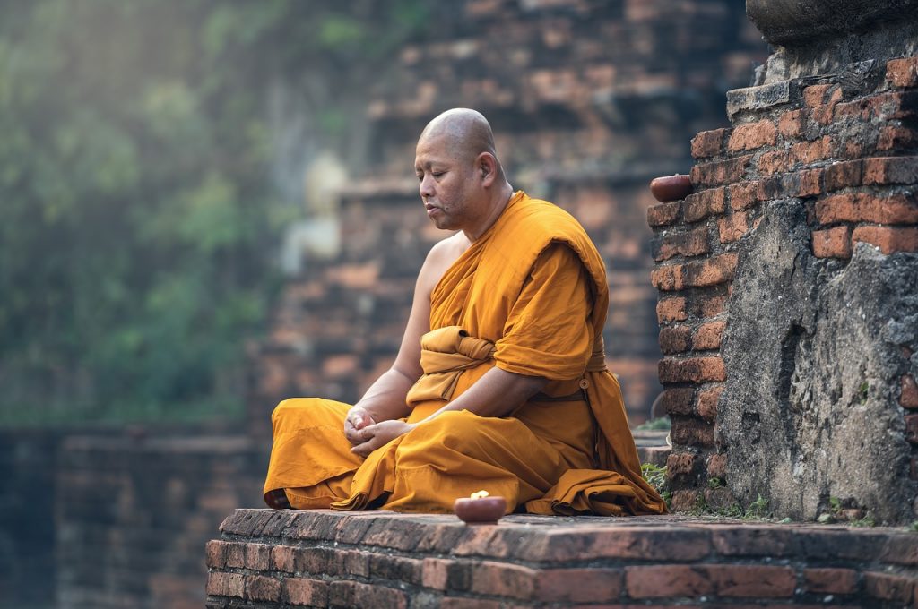 a Buddhist monk meditating on a rock outcropping