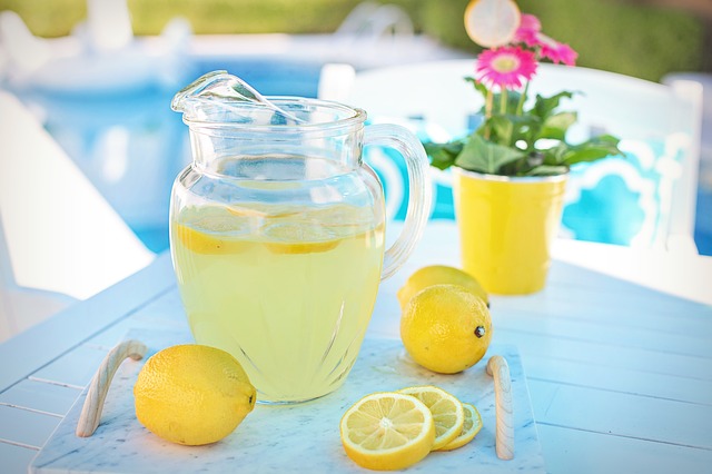 A pitcher of lemonade on a table with lemons